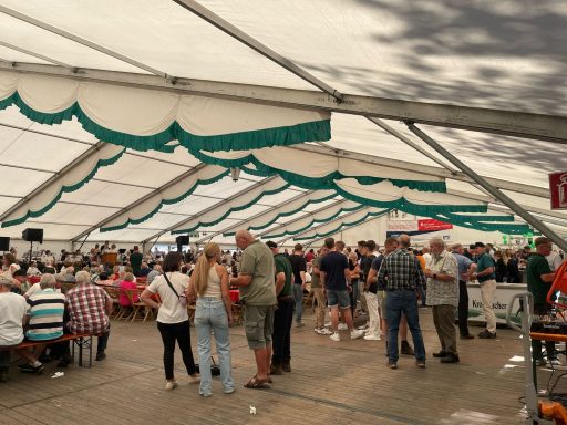 Menschenmengen in einem Zelt, die Essen und Getränke genießen, geselliges Beisammensein.