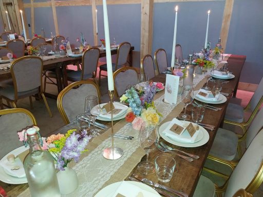 Elegant gedeckter Tisch mit Kerzen und Blumenarrangements für eine Feier.