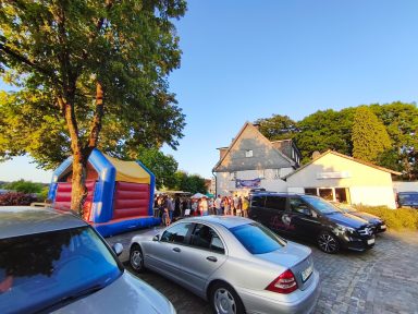 Eine belebte Veranstaltung mit einer Hüpfburg und Autos auf einem Parkplatz.