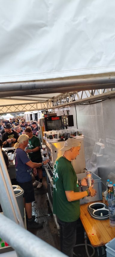 Zwei Personen in grünen Shirts arbeiten in einer Festzeltküche.