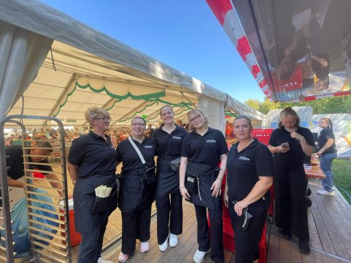 Sechs Personen in schwarzen Outfits stehen in einem festlichen Zelt.
