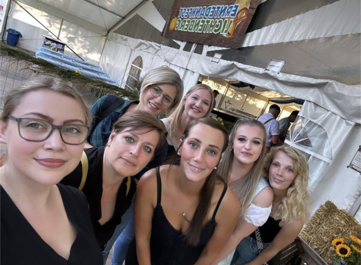 Gruppe von Frauen lächelt vor einem Festzelt.